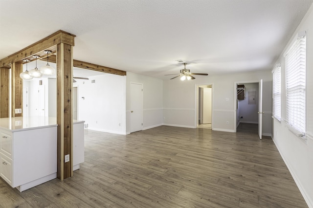 unfurnished living room featuring dark wood-type flooring and ceiling fan