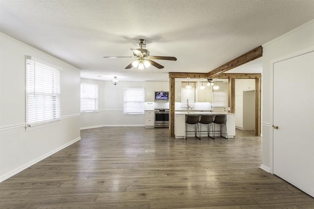 living room featuring dark hardwood / wood-style floors, sink, ceiling fan, a textured ceiling, and beam ceiling