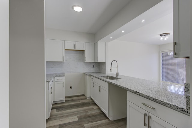 kitchen with white cabinetry, dark hardwood / wood-style flooring, sink, and light stone counters