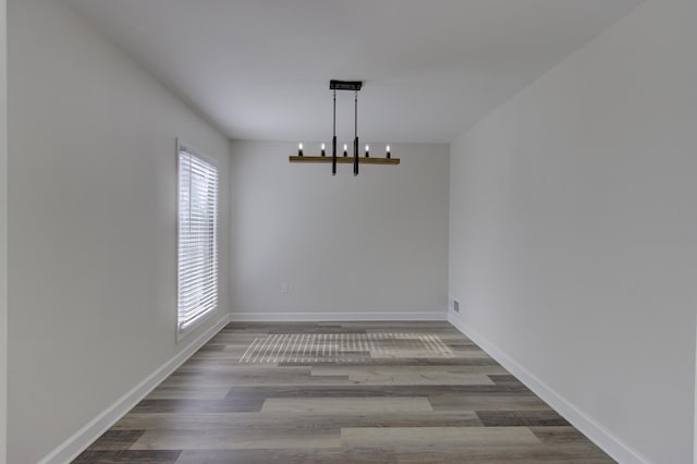 unfurnished dining area featuring hardwood / wood-style floors and a notable chandelier