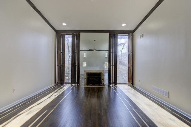 interior space with dark hardwood / wood-style flooring, crown molding, and a premium fireplace