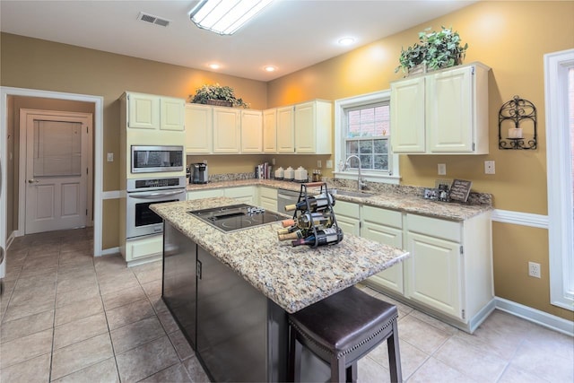 kitchen with a kitchen island, sink, a kitchen breakfast bar, light stone counters, and stainless steel appliances