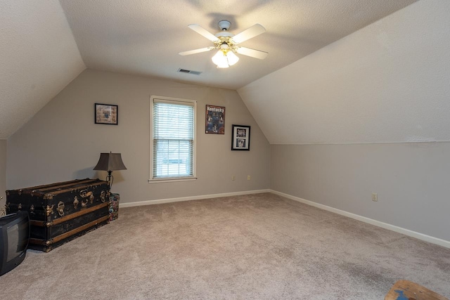 bonus room with ceiling fan, lofted ceiling, light carpet, and a textured ceiling