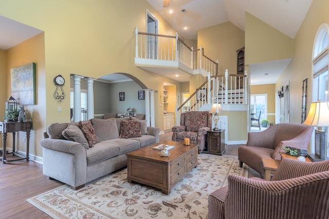 living room with high vaulted ceiling, decorative columns, and light wood-type flooring