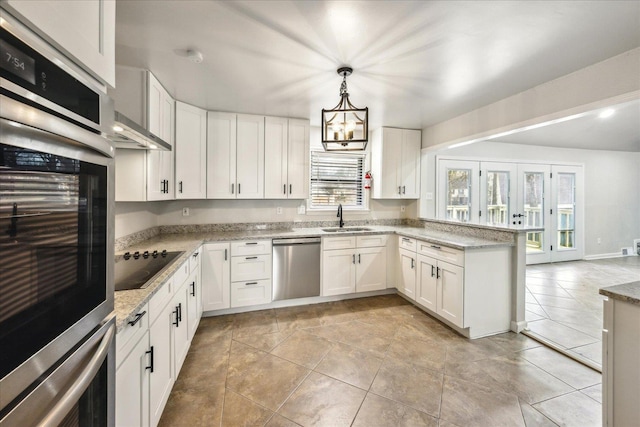 kitchen with appliances with stainless steel finishes, pendant lighting, sink, white cabinets, and light stone countertops