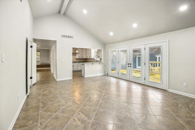 unfurnished living room featuring sink, light tile patterned floors, high vaulted ceiling, french doors, and beamed ceiling