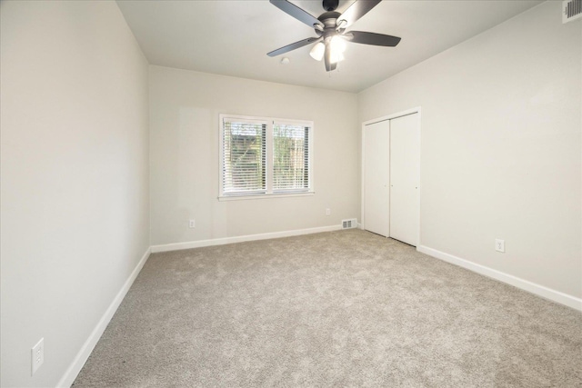 unfurnished bedroom with ceiling fan, light colored carpet, and a closet