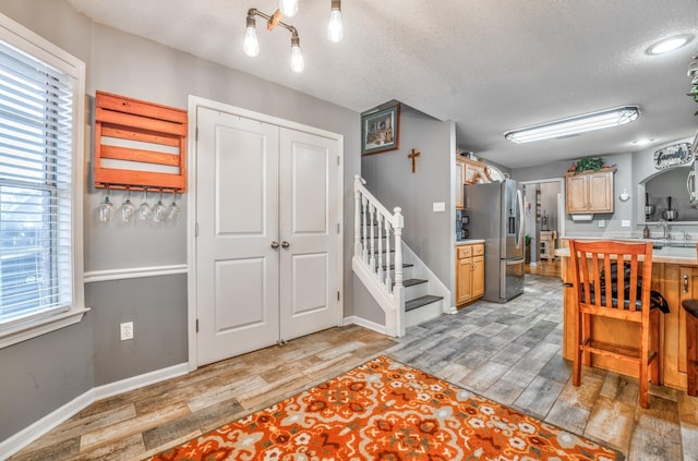 kitchen with stainless steel refrigerator with ice dispenser, a textured ceiling, light hardwood / wood-style flooring, and light brown cabinets