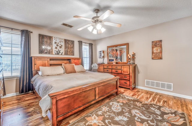 bedroom with ceiling fan, hardwood / wood-style floors, and a textured ceiling