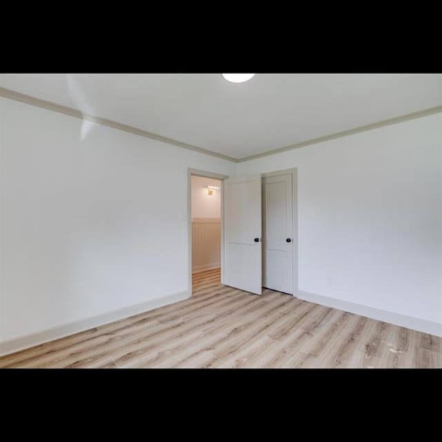 unfurnished room featuring crown molding and light wood-type flooring