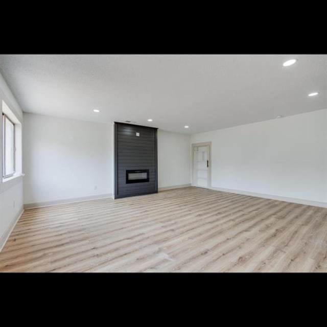 unfurnished living room with a fireplace and light hardwood / wood-style floors