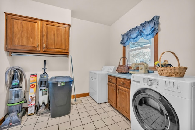 clothes washing area featuring light tile patterned floors, washer and clothes dryer, and cabinets