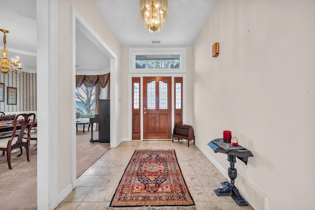 tiled foyer entrance featuring an inviting chandelier and ornamental molding