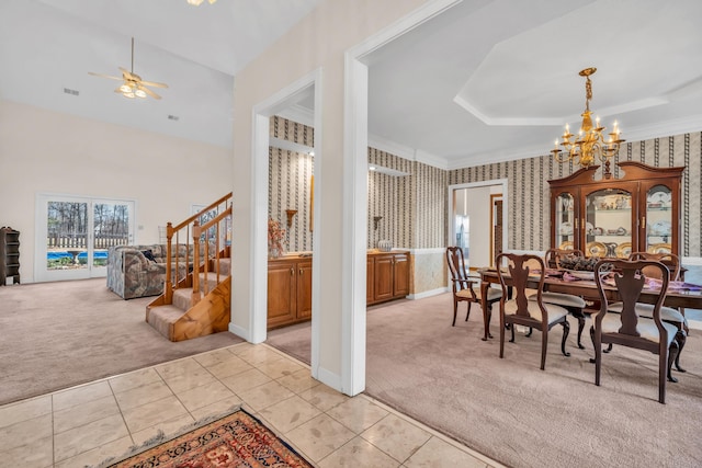 dining space with crown molding, a tray ceiling, ceiling fan with notable chandelier, and light colored carpet