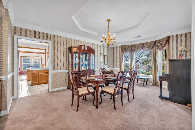 dining area with a raised ceiling, light carpet, and a chandelier