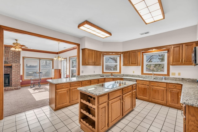 kitchen with sink, a center island, black electric stovetop, light carpet, and a brick fireplace