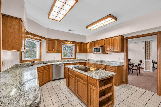 kitchen with light stone counters, stainless steel appliances, a center island, and light tile patterned flooring