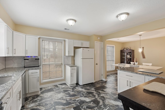 kitchen with dishwasher, backsplash, white refrigerator, white cabinets, and decorative light fixtures