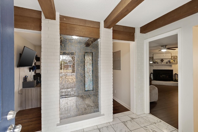 bathroom with a brick fireplace, ceiling fan, beamed ceiling, and ornate columns