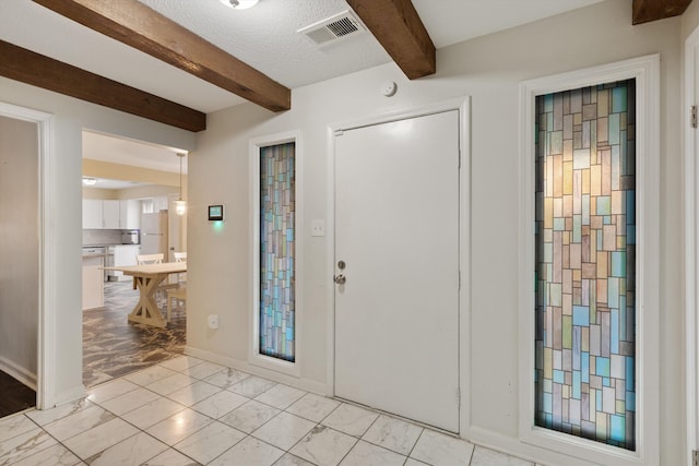 entryway featuring a textured ceiling and beamed ceiling