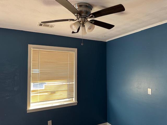 spare room with crown molding and ceiling fan