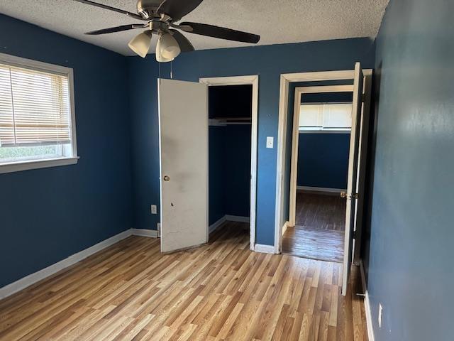 unfurnished bedroom with ceiling fan, a closet, a textured ceiling, and light wood-type flooring