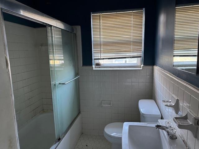 full bathroom featuring sink, enclosed tub / shower combo, tile patterned flooring, tile walls, and toilet