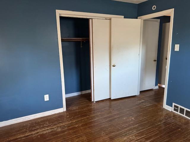 unfurnished bedroom featuring dark hardwood / wood-style flooring and a closet