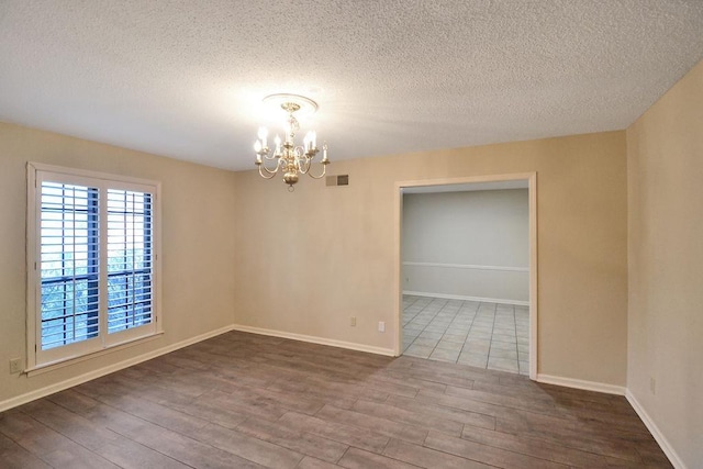 spare room with hardwood / wood-style flooring, a textured ceiling, and an inviting chandelier