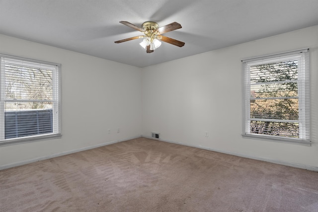 carpeted empty room with a wealth of natural light and ceiling fan