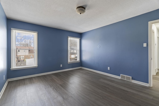 spare room featuring dark hardwood / wood-style floors and a textured ceiling