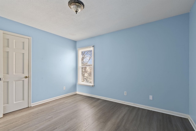 empty room with hardwood / wood-style flooring and a textured ceiling