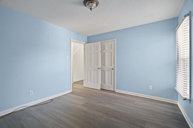 unfurnished bedroom with hardwood / wood-style flooring, a closet, and a textured ceiling