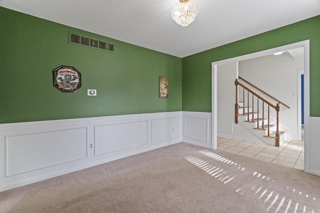 unfurnished room featuring light carpet and a notable chandelier