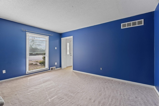 spare room with light colored carpet and a textured ceiling