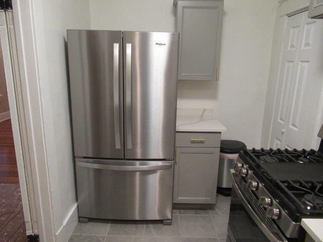 kitchen with appliances with stainless steel finishes, gray cabinets, and light tile patterned floors