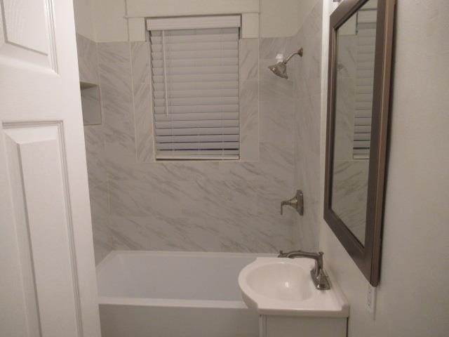 bathroom with tiled shower / bath combo and vanity