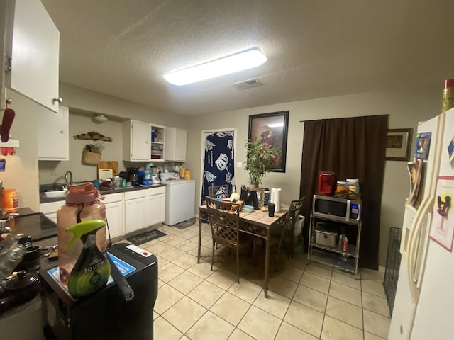 kitchen with washer / clothes dryer, light tile patterned floors, white cabinets, and white fridge