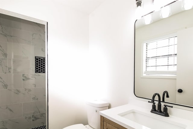 bathroom featuring tiled shower, vanity, and toilet