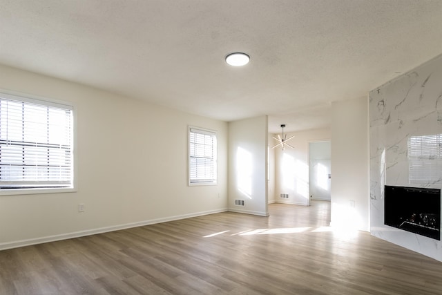 unfurnished living room featuring hardwood / wood-style floors, a fireplace, and a textured ceiling