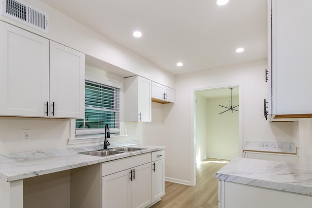 kitchen featuring white cabinetry, light stone countertops, sink, and light hardwood / wood-style flooring