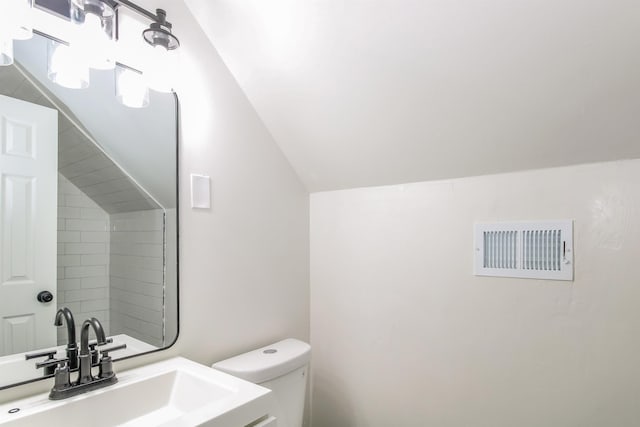 bathroom with lofted ceiling, toilet, and sink