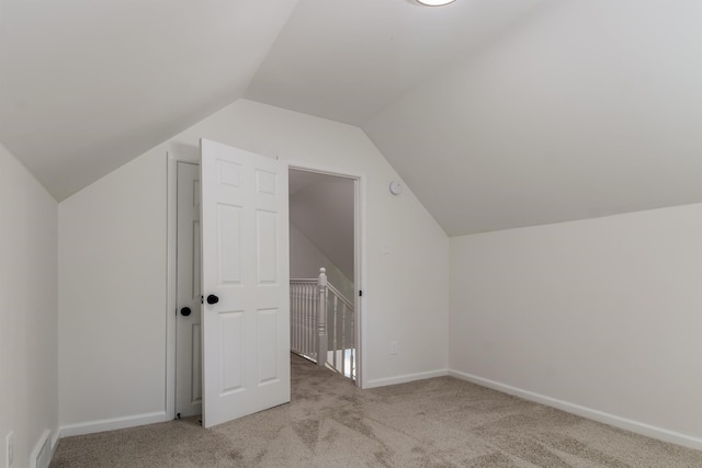 bonus room with vaulted ceiling and light carpet