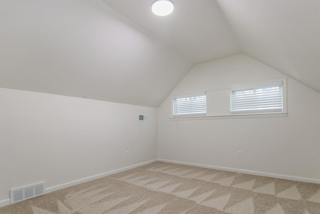 additional living space featuring vaulted ceiling and carpet flooring