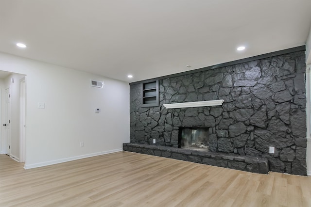 unfurnished living room featuring a stone fireplace and light hardwood / wood-style floors