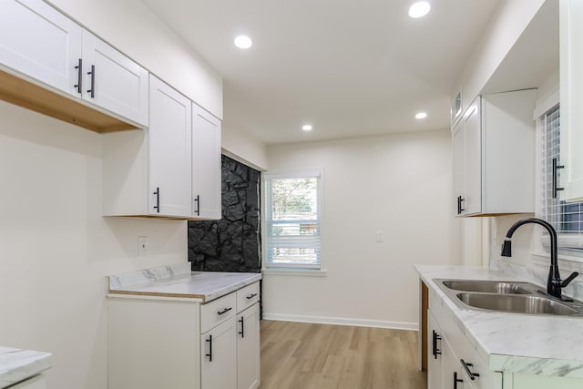 kitchen with sink, light hardwood / wood-style flooring, and white cabinets