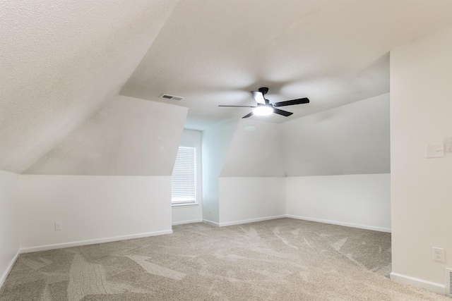 additional living space with vaulted ceiling, light colored carpet, and a textured ceiling