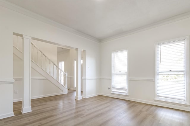 unfurnished living room with decorative columns, crown molding, and light wood-type flooring