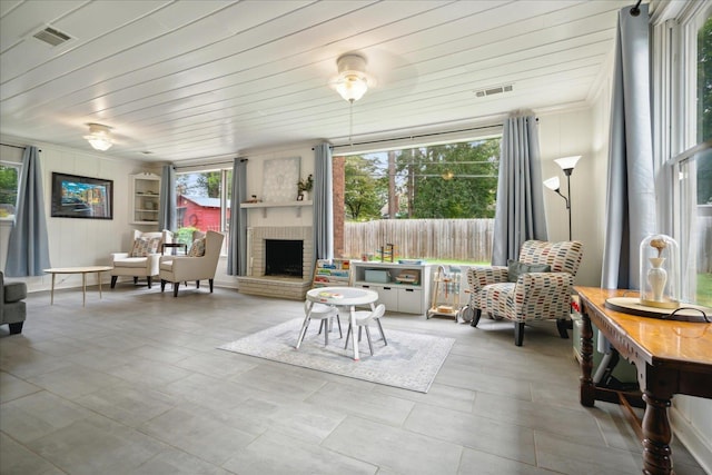 interior space with wood ceiling, a brick fireplace, and a wealth of natural light