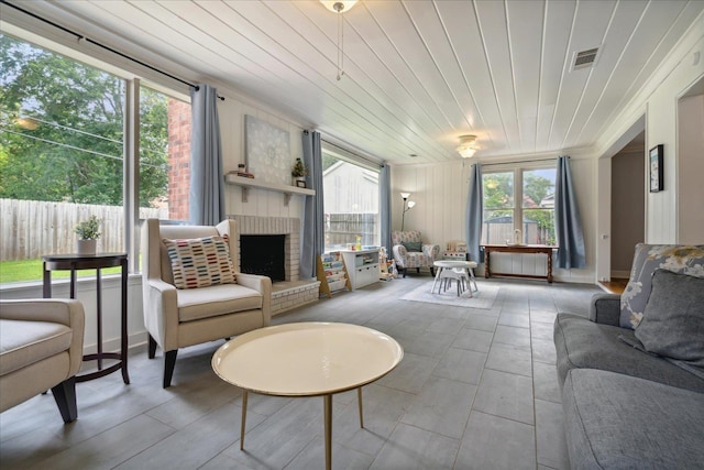 sunroom with a brick fireplace and wood ceiling